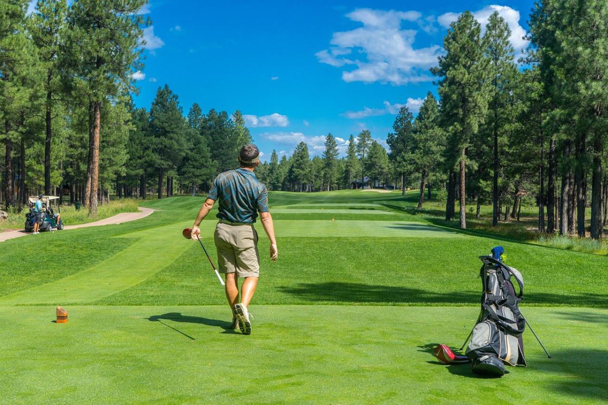 A golfer mid swing on the fairway, VIP Buses golf society transport