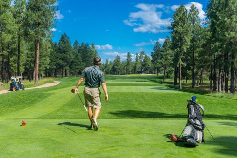 A golfer mid swing on the fairway, VIP Buses golf society transport