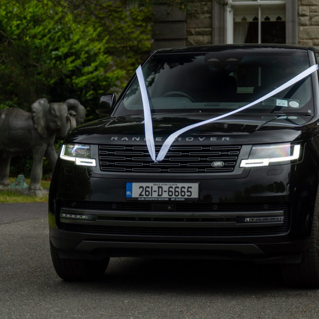 VIP Buses Black Range Rover Vogue SWB dressed with white wedding ribbons by a stone elephant