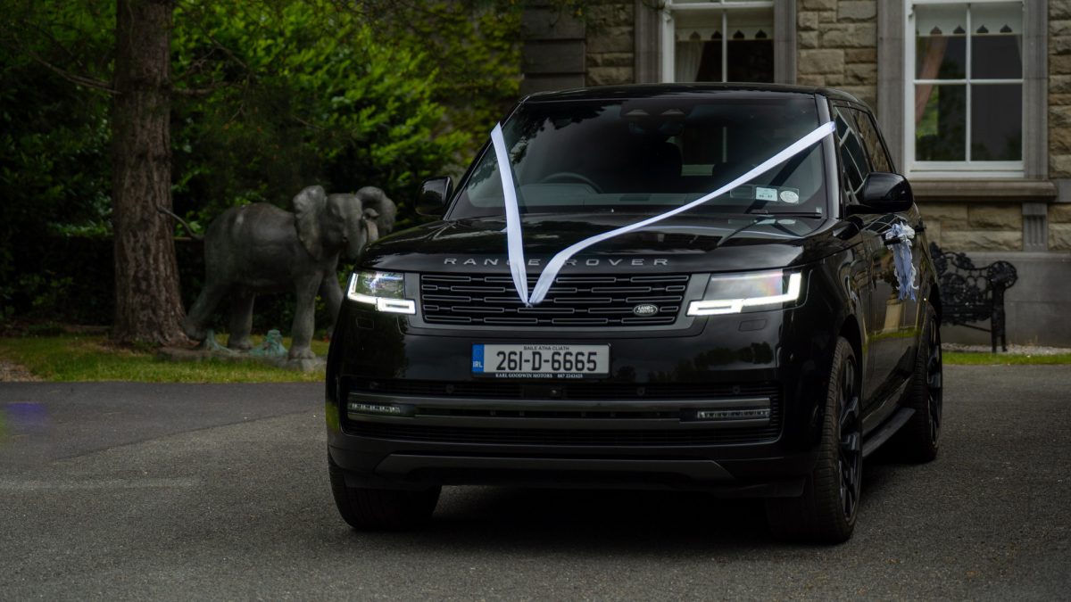 VIP Buses Black Range Rover Vogue SWB dressed with white wedding ribbons by a stone elephant