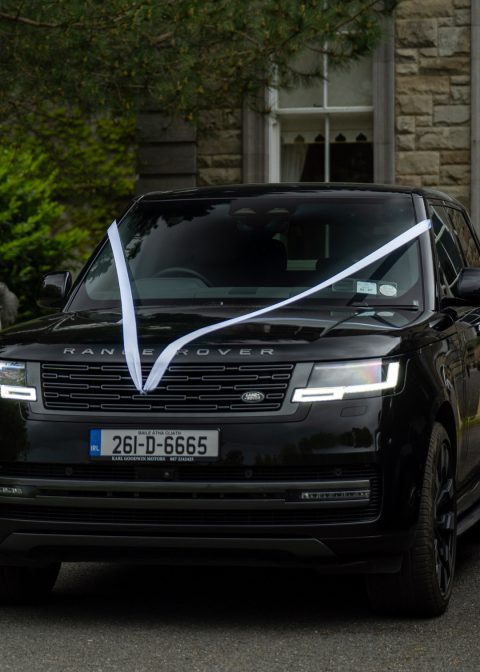 VIP Buses Black Range Rover Vogue SWB dressed with white wedding ribbons by a stone elephant