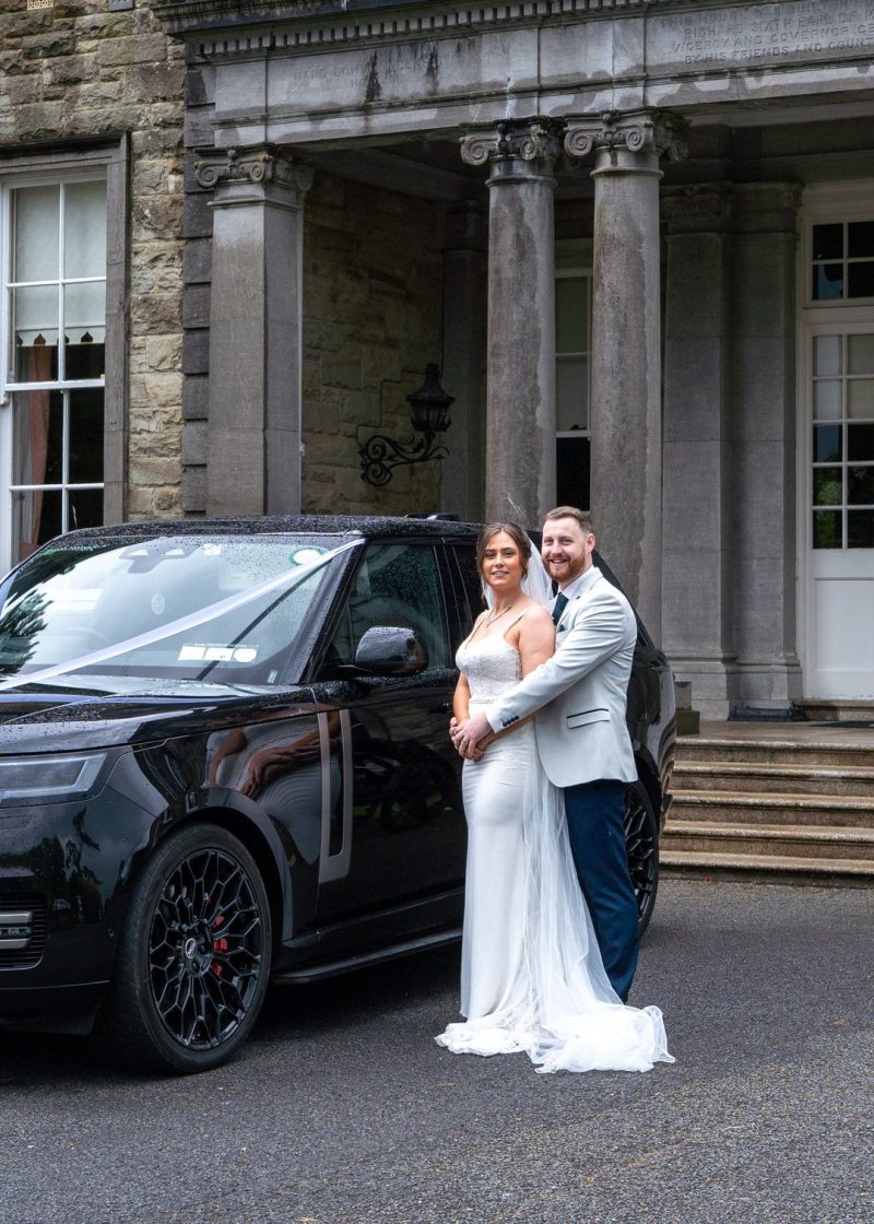 VIP Buses Black Range Rover Vogue SWB with the couple embracing beside the entrance steps