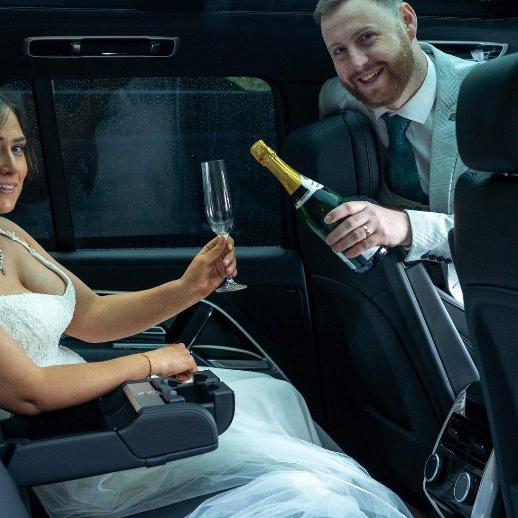 VIP Buses Black Range Rover Vogue SWB interior with the groom pouring champagne for the bride