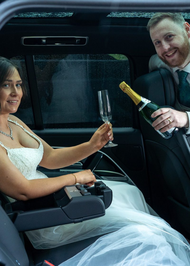VIP Buses Black Range Rover Vogue SWB interior with the groom pouring champagne for the bride