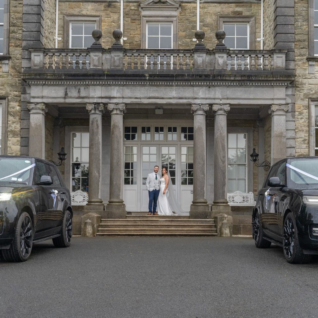 VIP Buses Black Range Rover Vogue SWB pair framing the bride and groom on the entrance steps