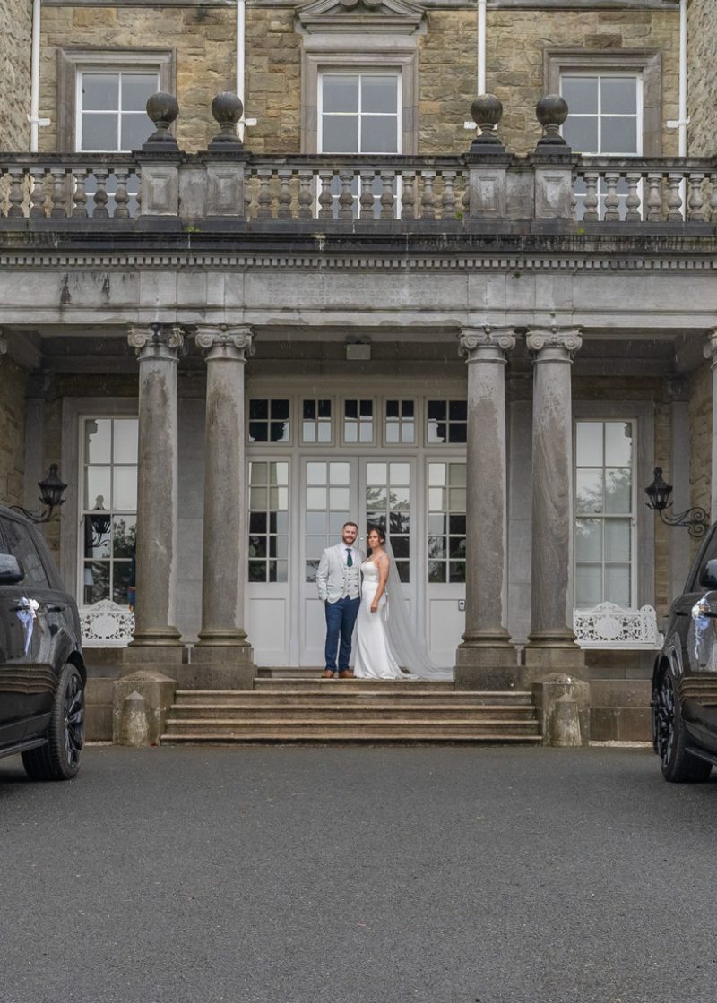 VIP Buses Black Range Rover Vogue SWB pair framing the bride and groom on the entrance steps