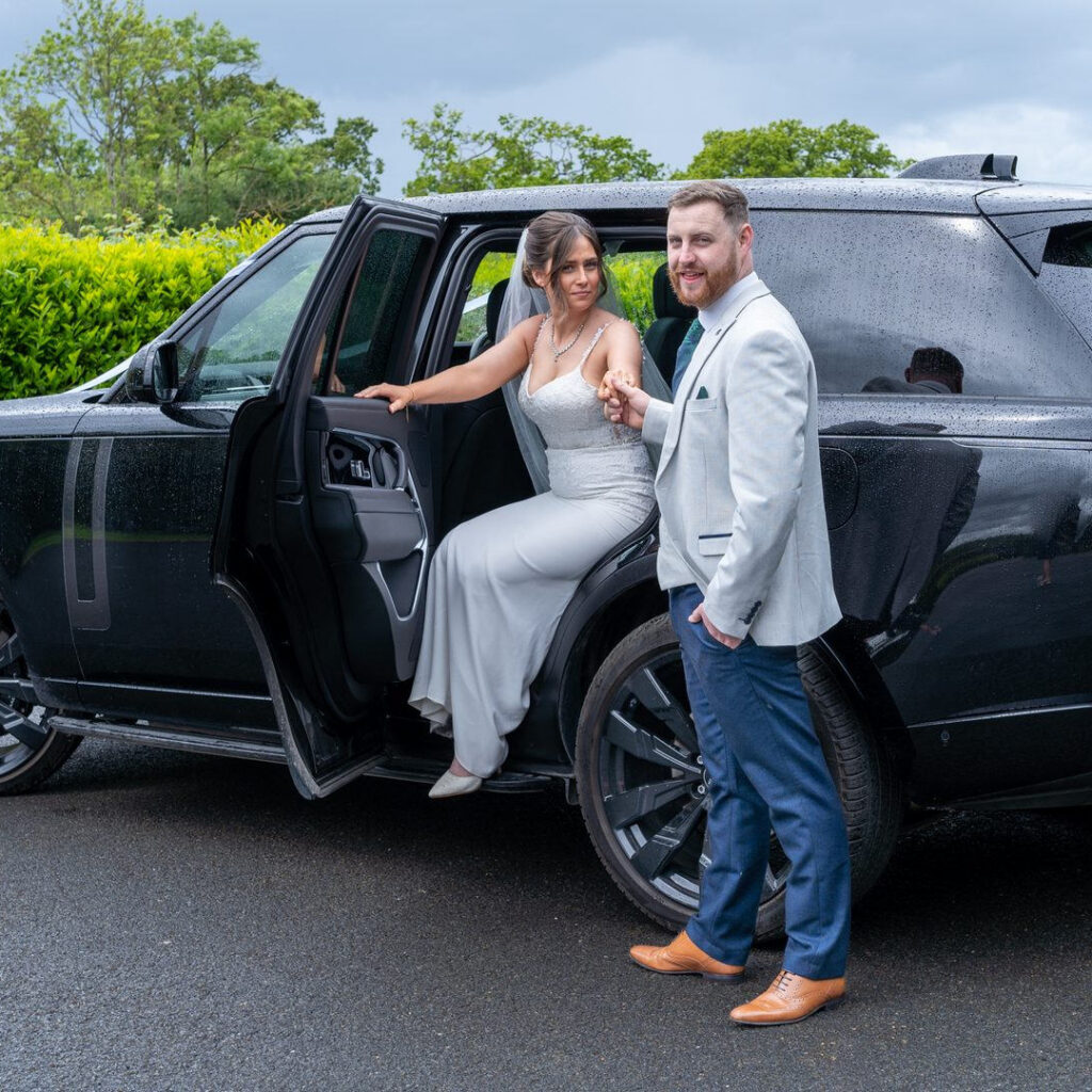 VIP Buses Black Range Rover Vogue SWB with the bride stepping out as the groom leads her hand