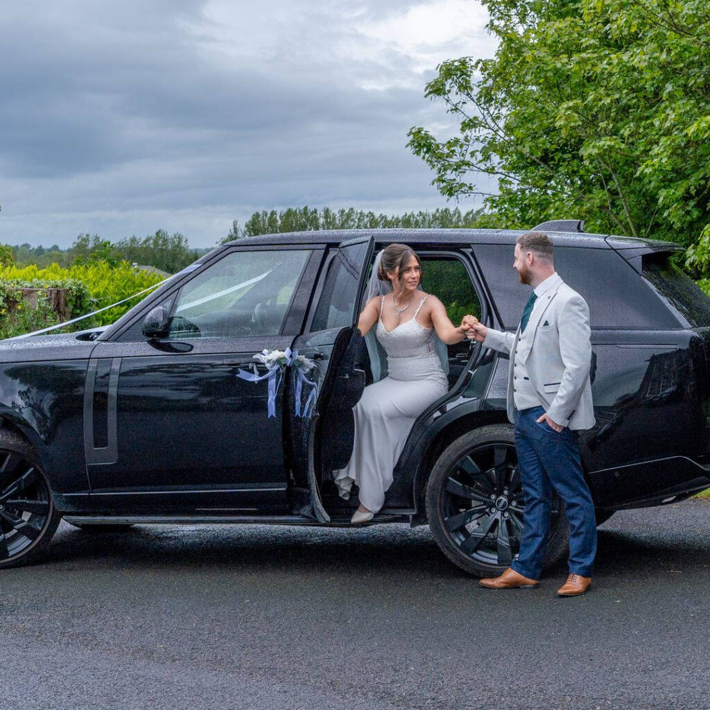 VIP Buses Black Range Rover Vogue SWB with the groom taking the brides hand as she steps out