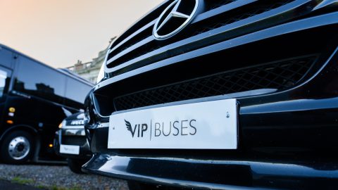 VIP Buses Fleet Lineup Mercedes grille and branded plate at dusk with the fleet behind