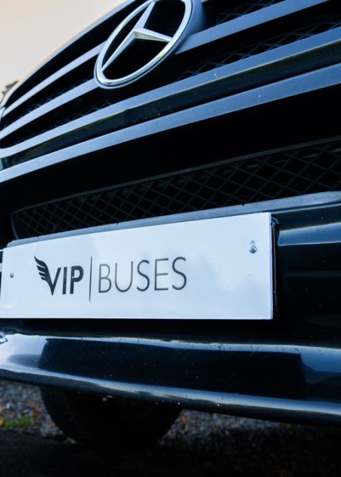 VIP Buses Fleet Lineup Mercedes grille and branded plate at dusk with the fleet behind