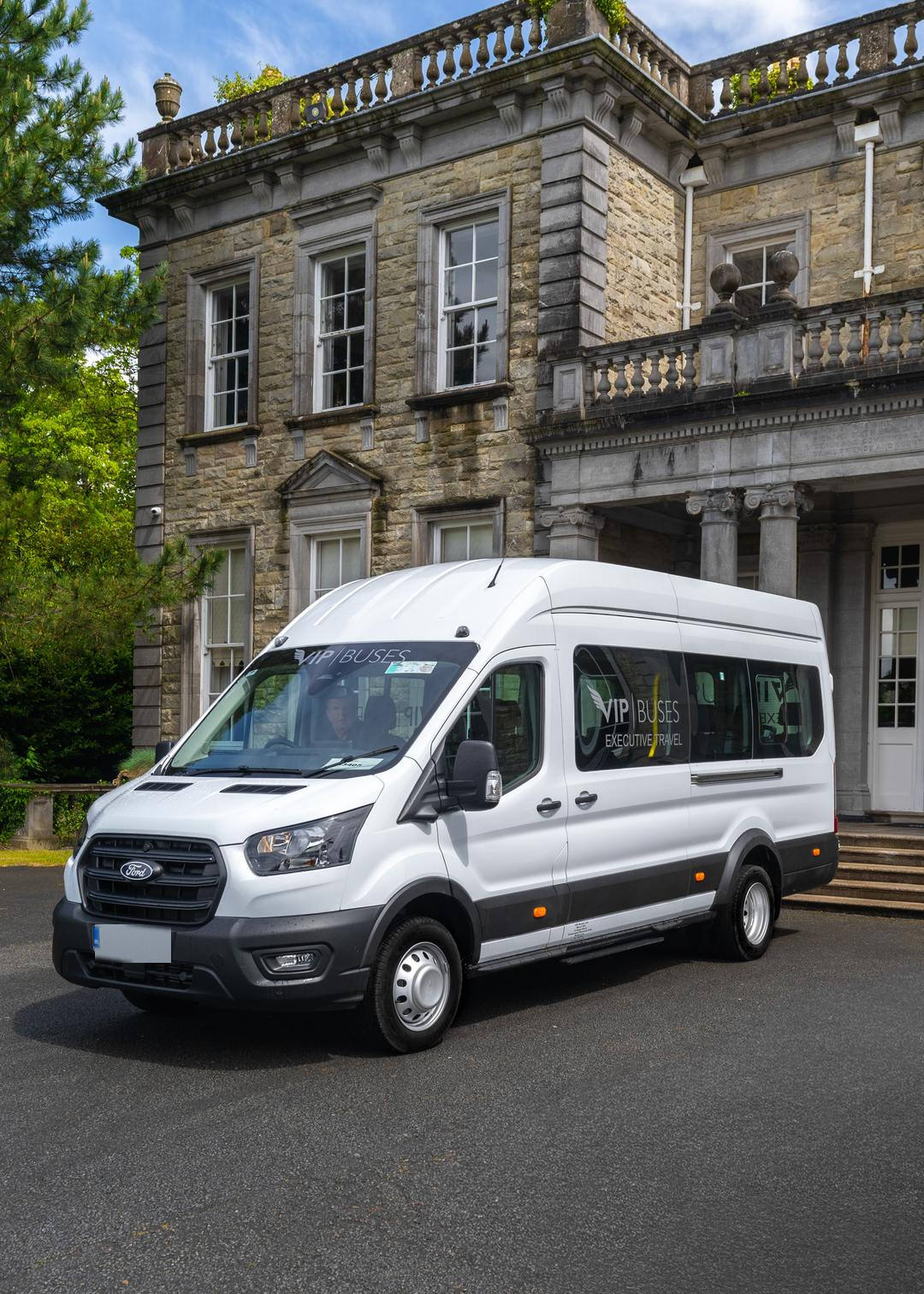 VIP Buses Ford Transit 17 Seater Minibus front three quarter below the house facade