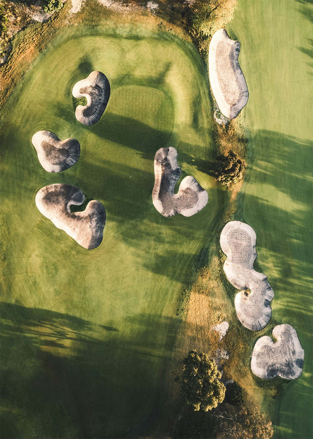 Golf trip aerial view of bunkers around a sunlit green
