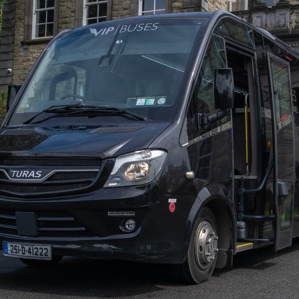 VIP Buses Turas 33 Seater Coach front three quarter with the door open by the portico